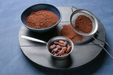 Bowls with cacao powder and beans on dark background