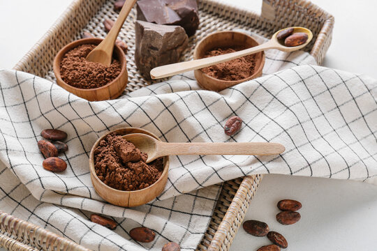 Tray with cacao powder, beans and chocolate on white background