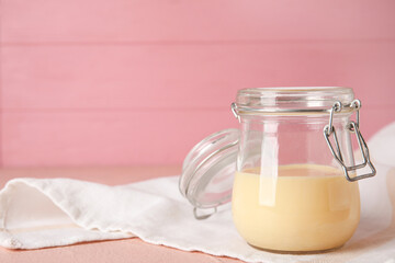 Jar with sweet condensed milk on color wooden background