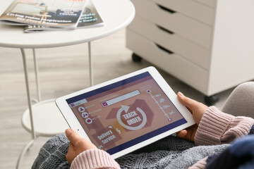 Woman holding tablet computer with open page of delivery service application at home