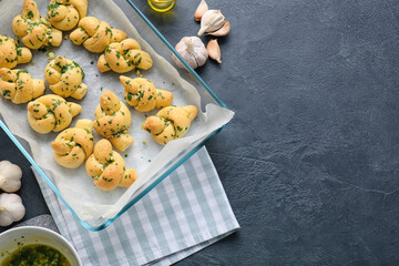 Baking dish with tasty garlic buns on dark background