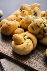 Board with tasty garlic buns on dark background, closeup