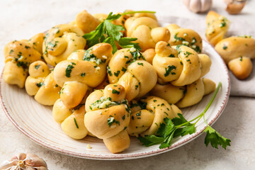 Plate with tasty garlic buns on light background