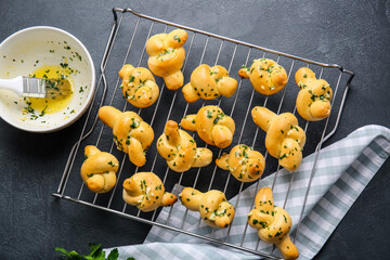 Baking rack with tasty garlic buns on dark background