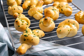 Baking rack with tasty garlic buns on dark background