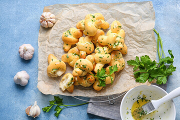 Parchment with tasty garlic buns on color background