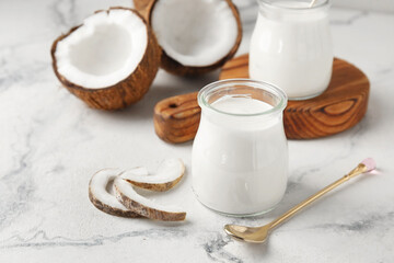 Jars of tasty coconut yogurt on light background