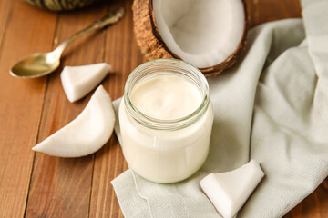 Jar of tasty coconut yogurt on wooden background