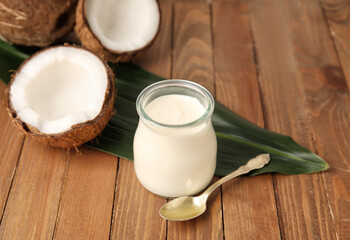 Jar of tasty coconut yogurt on wooden background