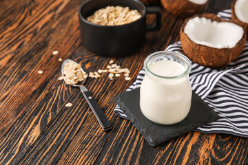 Jar of tasty coconut yogurt on wooden background