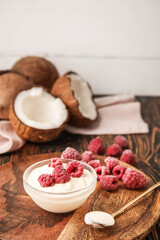 Tasty coconut yogurt with raspberry on wooden background