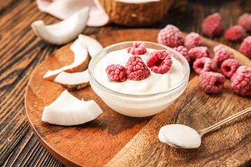 Tasty coconut yogurt with raspberry on wooden background