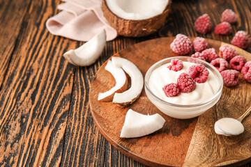 Obraz na płótnie Canvas Tasty coconut yogurt with raspberry on wooden background