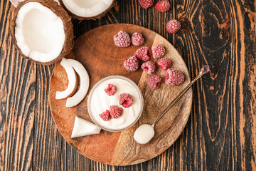 Fototapeta na wymiar Tasty coconut yogurt with raspberry on wooden background