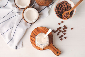 Jar of tasty coconut yogurt on light wooden background