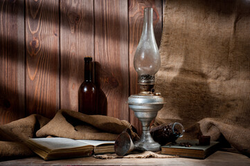 Obraz na płótnie Canvas A vintage kerosene lamp covered in dust and soot, shot against a background of wood panels and burlap.