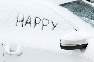 Word HAPPY written on snow covered car window