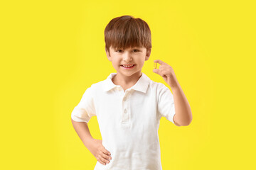Little boy with fish oil on color background