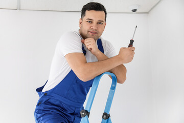 Worker installing CCTV camera in room
