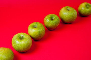 Large green apples, ripe and juicy. Photographed against a uniform red background.