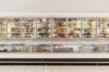 Glass display cases in the frozen food section of a supermarket. Front view. Blurred.