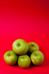 Large green apples, ripe and juicy. Photographed against a uniform red background.
