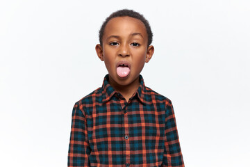 Portrait of nasty mischievous little black boy grimacing, making disgusting facial expression,...