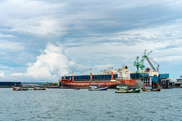 Large general cargo ship for transportation import export goods moored in the harbor and in the process of loading and unloading or conveying products