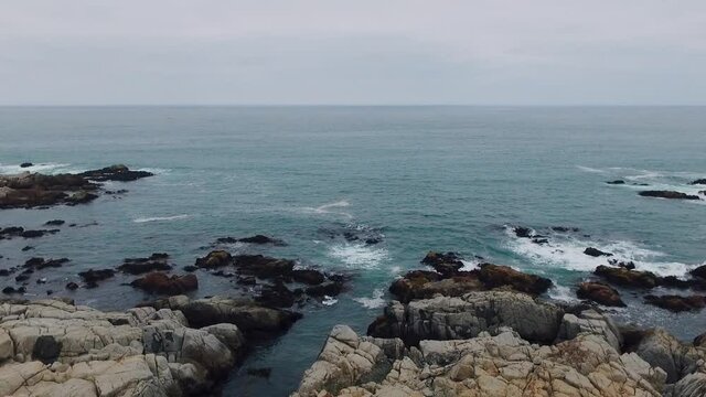 Aerial drone shot over the Chilean coast, cinematic and static stabilized video over the waves hitting the rocks