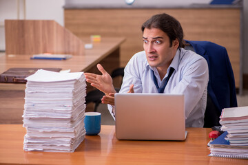 Young male employee unhappy with excessive work in the office