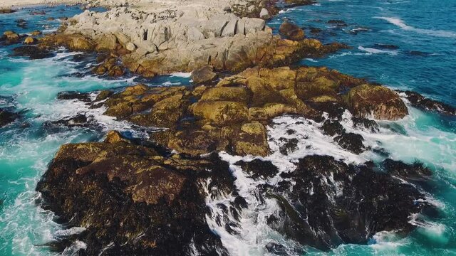 Aerial drone shot over the Chilean coast, cinematic and static stabilized video over the waves hitting the rocks