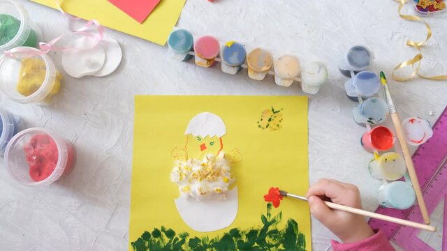 Child making card with Easter chick from colorful paper and cotton pad. Handmade. A project of children's creativity, handicrafts, crafts for kids.