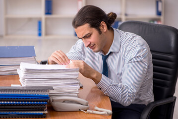 Young male employee unhappy with excessive work in the office