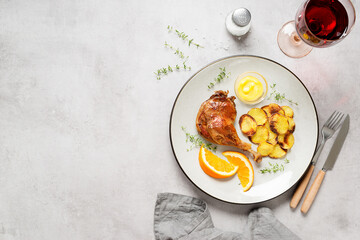 Duck leg confit served with potato chips and mustard sauce .Traditional french cuisine. Light gray background, top view. Space for text