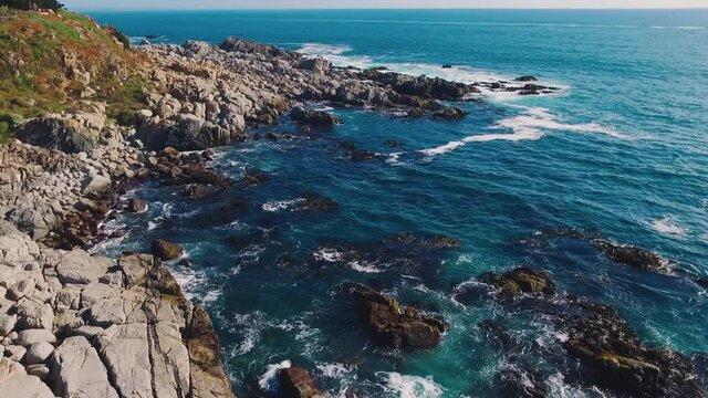 Aerial drone shot over the Chilean coast, cinematic and stabilized video moving over the waves hitting the rocks