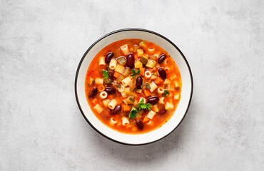 Vegetarian minestrone italian soup made with fresh vegetables, pasta and beans. Light gray...