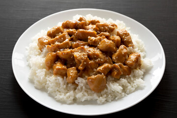 Homemade Orange Chicken with White Rice on a white plate on a black background, low angle view. Close-up.