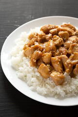 Homemade Orange Chicken with White Rice on a white plate on a black background, low angle view. Close-up.