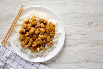 Homemade Orange Chicken with White Rice on a white plate on a white wooden background, top view. Overhead, from above, flat lay. Copy space.