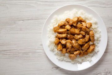 Homemade Orange Chicken with White Rice on a white plate on a white wooden background, top view. Overhead, from above, flat lay. Space for text.