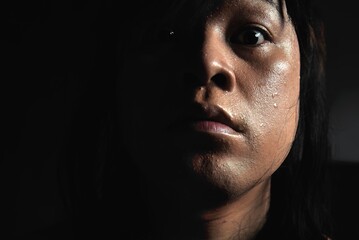 Sweaty face  And the tears of long-haired Asian men  On a black background  Expresses the...