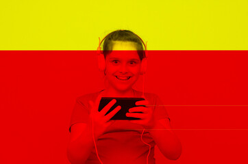 Gamer Kid. 10 years old child holding a phone video game playing a video game in a computer graphic light composition ambient. Studio shot. Gaming addiction concept yellow and red overlay