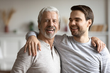 Portrait of happy middle-aged Caucasian father hug adult grownup 30s son, feel proud thankful. Smiling millennial 20s man embrace mature optimistic grey-haired dad parent. Family unity concept.