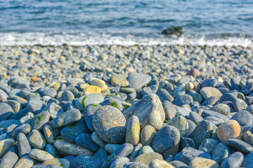 The wide blue ocean seen from the beach with a pebble rock