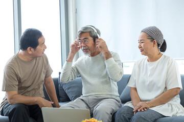 Old men and women listening to music with laptop in the living room. Senior friends group hangout, Older people meeting.