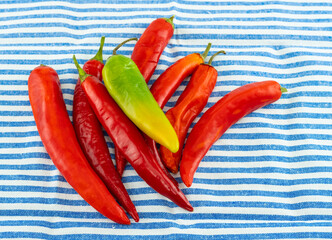 scattering of red chili peppers on a striped background tablecloth white and blue stripes
