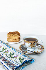Gold cup of tea. A slice of honey cake in focus. Vertical photography.