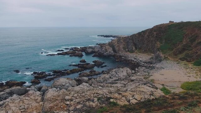 Aerial drone shot over the Chilean coast of El Quisco Chile, static drone in the air recording the waves crashing on the rocks