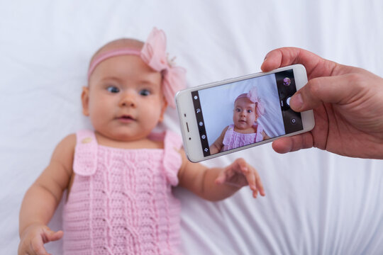 Newborn baby girl is photographed on a mobile phone