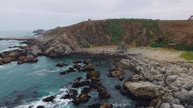 Aerial drone shot over the chilean coast of punta de tralca Chile, traveling over the rocky creek along with the waves